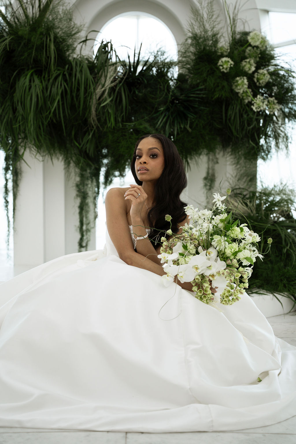bride sitting down in wedding dress holding bouquet of flowers