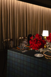 Rehearsal dinner table details with red roses, blackwatch linens, and table lamps in Chicago, IL