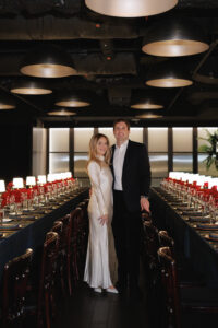 Bride and groom standing in between rehearsal dinner tables