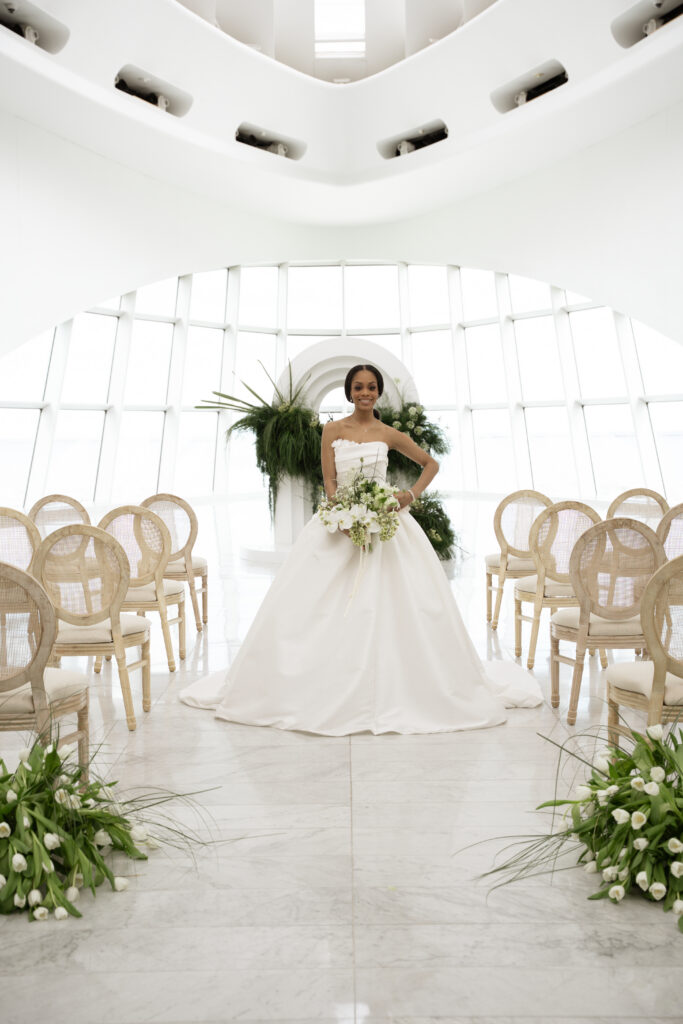 bride standing in center of ceremony aisle in modern art museum